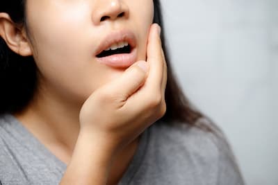 A woman with a toothache holds her jaw